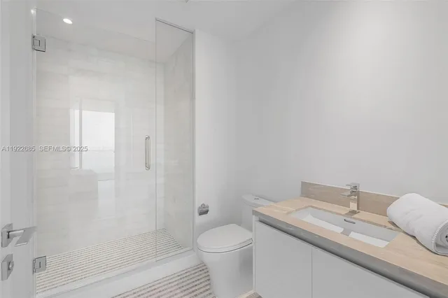 a bathroom with a granite countertop sink a toilet and shower