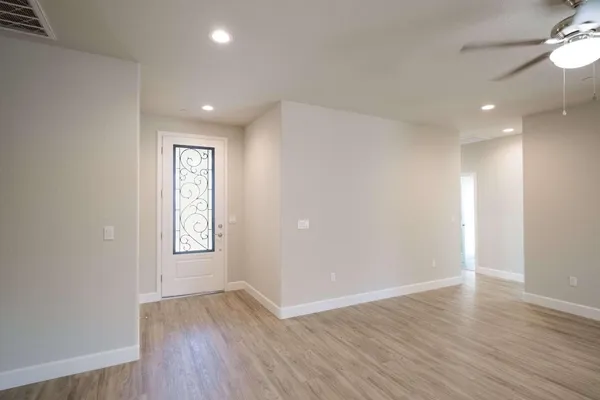 an empty room with wooden floor fan and windows