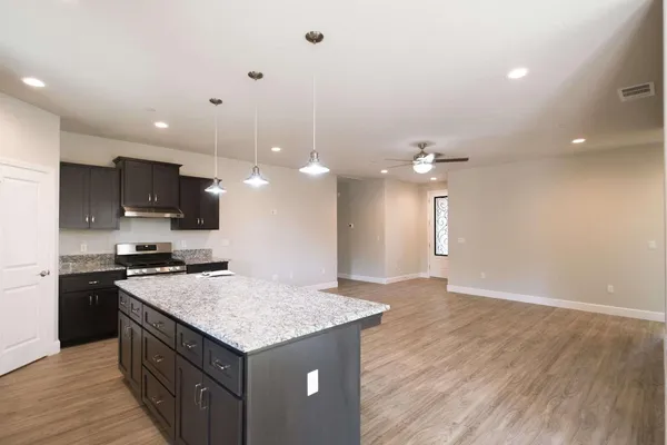 a view of kitchen with stainless steel appliances granite countertop a stove top oven a sink dishwasher a refrigerator and white cabinets with wooden floor
