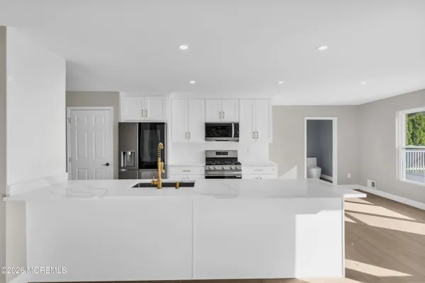 a kitchen with granite countertop a sink and white cabinets with wooden floor