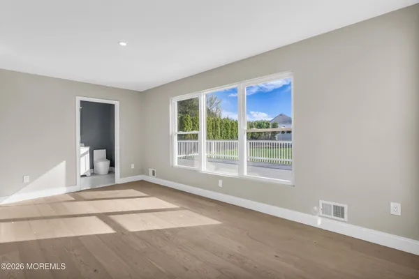 a view of an empty room with window and wooden floor