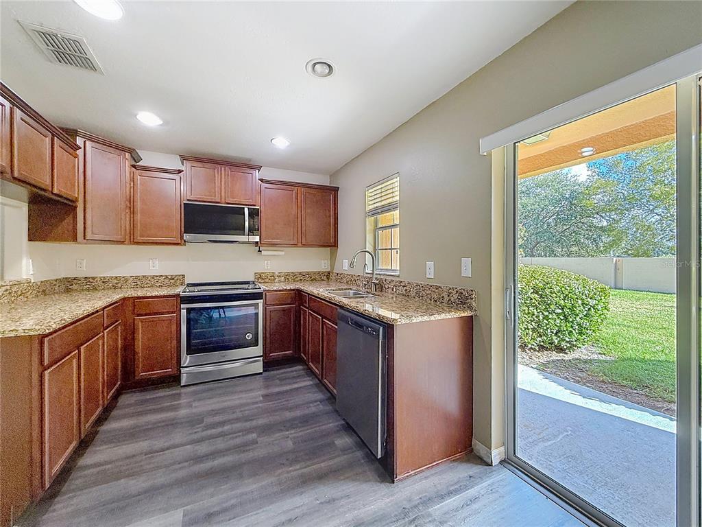 9873 Trumpet Vine Loop Trinity, FL 34655 - Photo 19 of 40 a large kitchen with stainless steel appliances granite countertop a stove a sink and a refrigerator