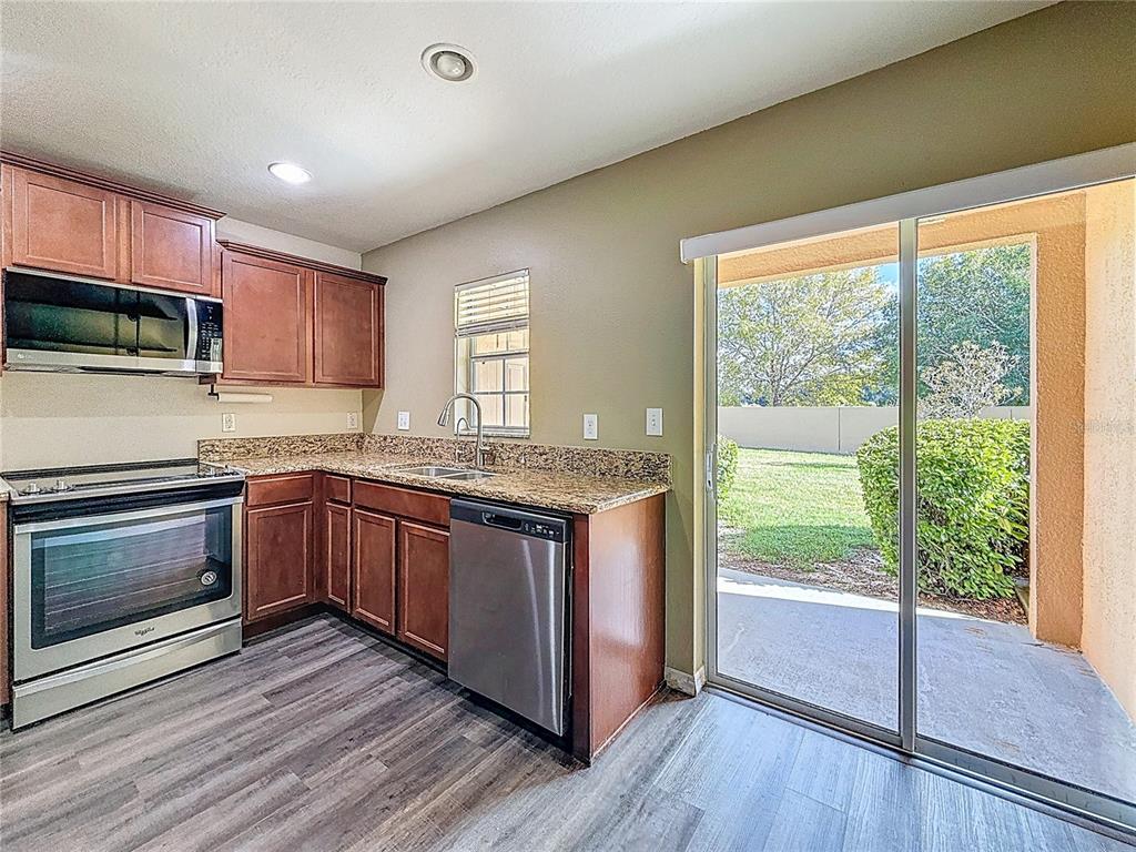 9873 Trumpet Vine Loop Trinity, FL 34655 - Photo 20 of 40 a kitchen with granite countertop wooden floors a sink and a stove