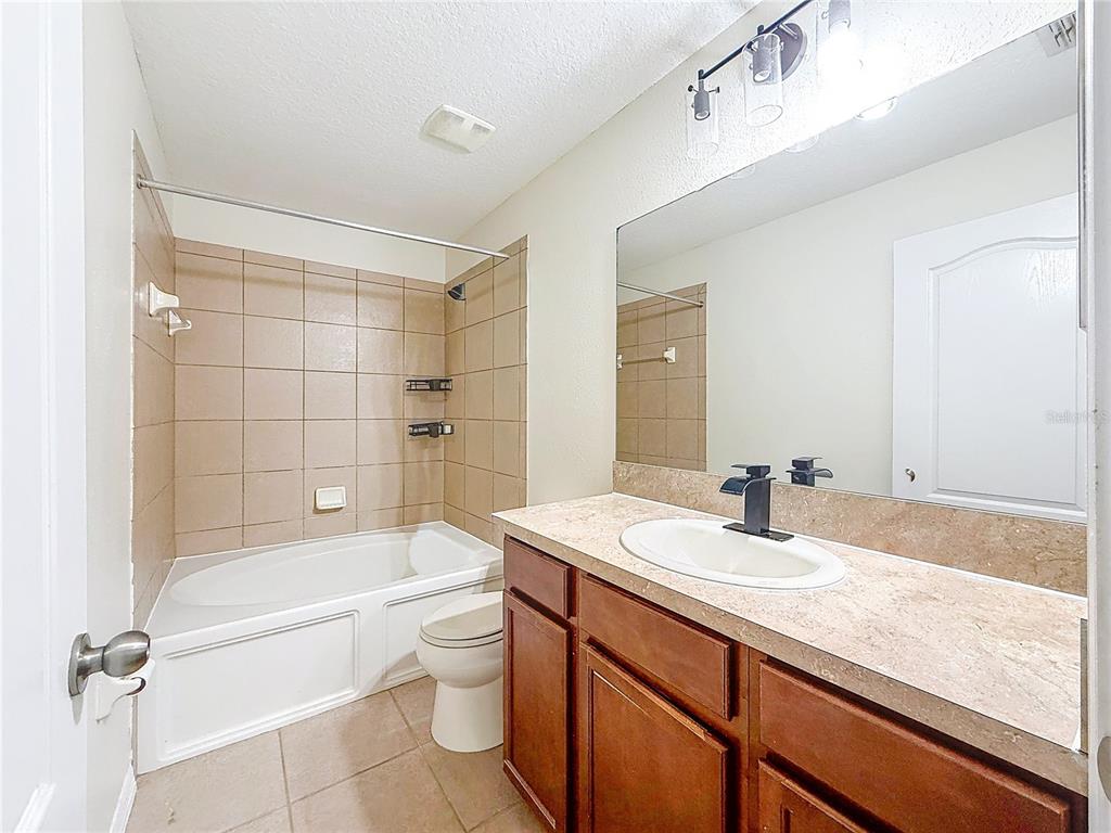 9873 Trumpet Vine Loop Trinity, FL 34655 - Photo 24 of 40 a bathroom with a granite countertop sink a toilet and bathtub