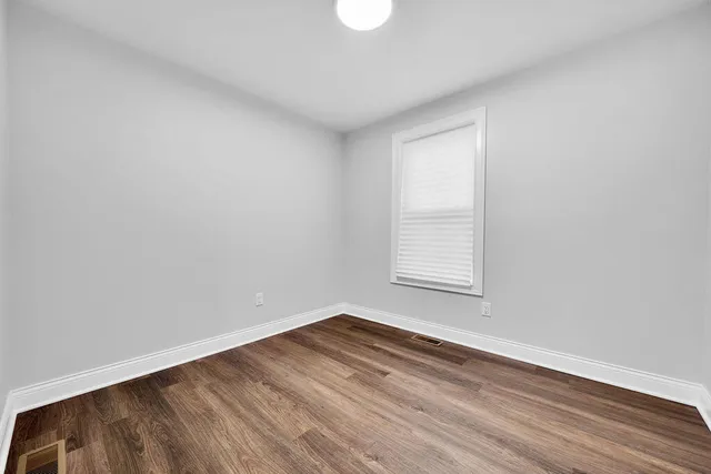 an empty room with wooden floor and stairs