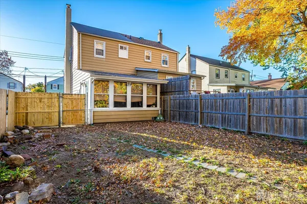 a view of a backyard with large trees and wooden fence