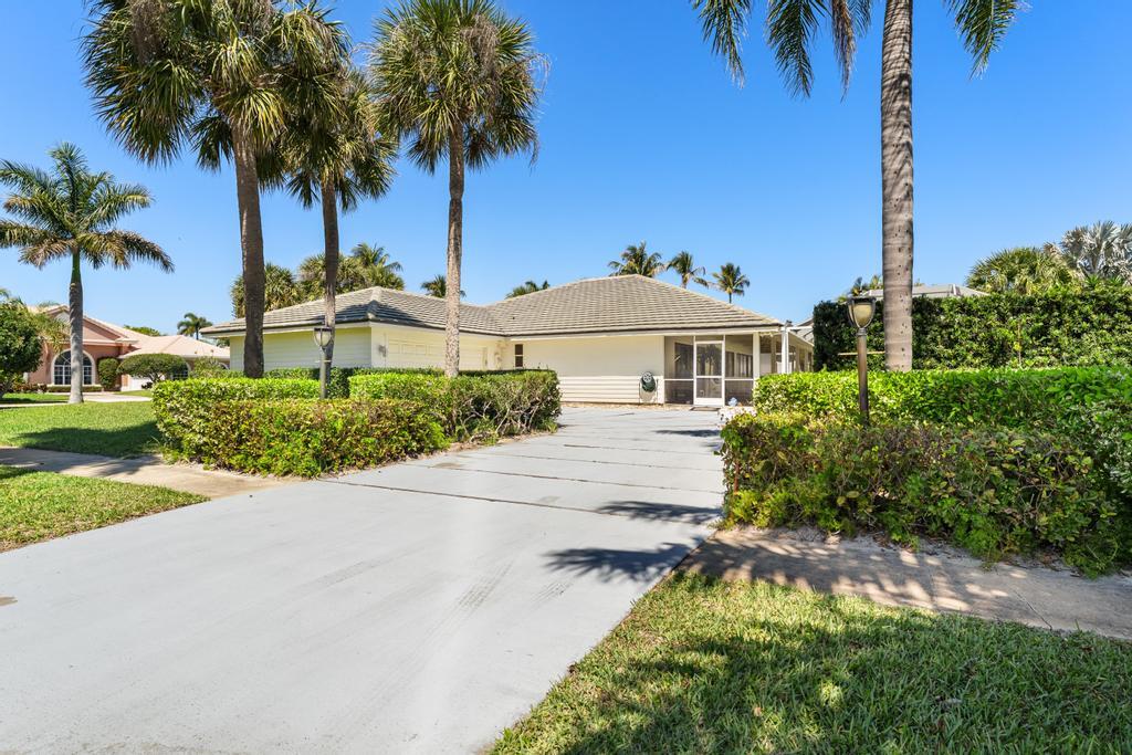 108 Pegasus Drive Jupiter, FL 33477 - Photo 58 of 74 a front view of a house with a yard and palm trees