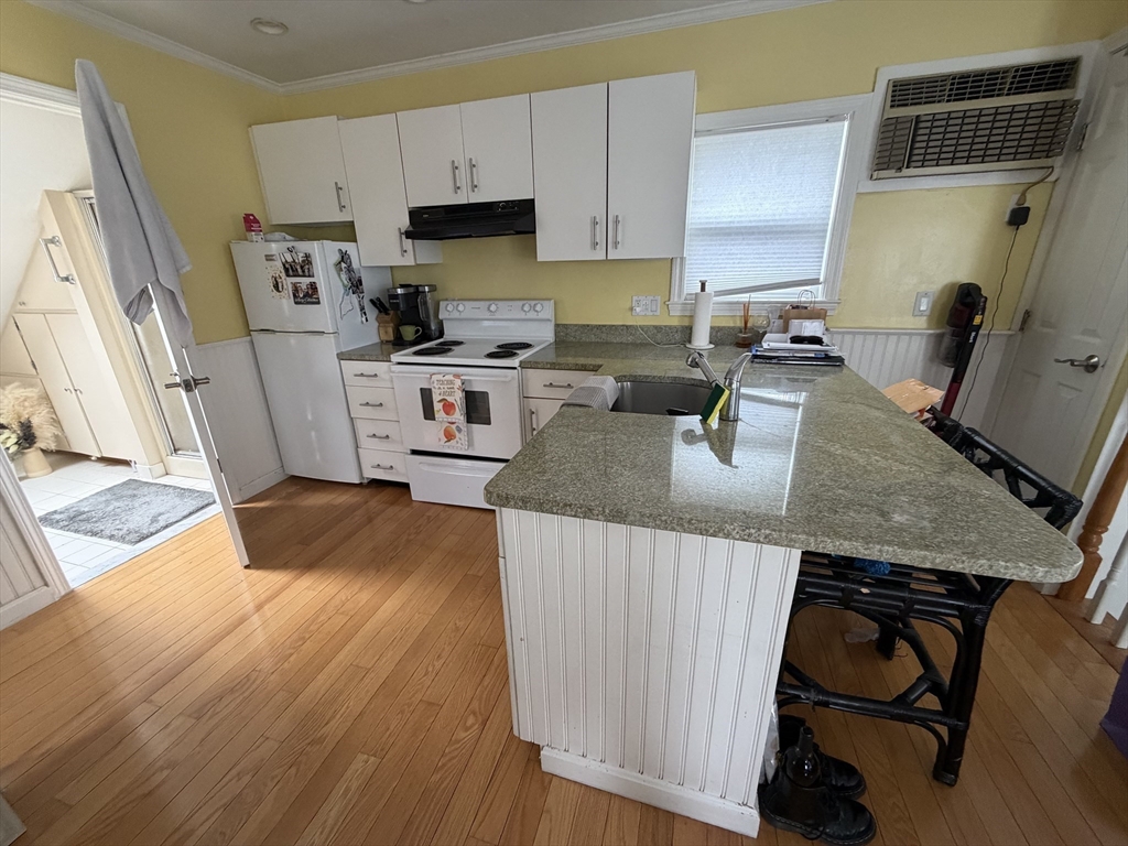 114 Parish Road Needham, MA 02494 - Photo 12 of 20 a kitchen with granite countertop a refrigerator a stove a sink dishwasher and white cabinets with wooden floor