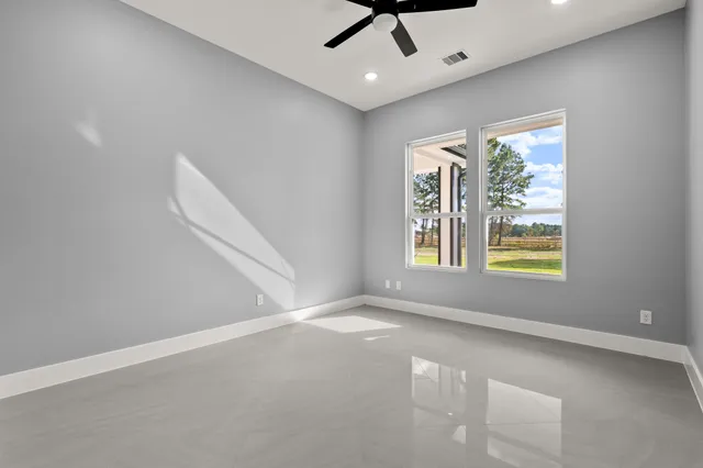 an empty room with windows and fan