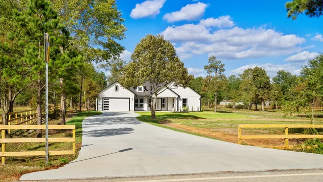 a view of big house with a big yard and large trees
