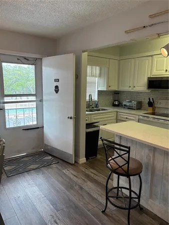 a kitchen with stainless steel appliances granite countertop a stove a sink dishwasher a microwave oven and a dining table with wooden floor