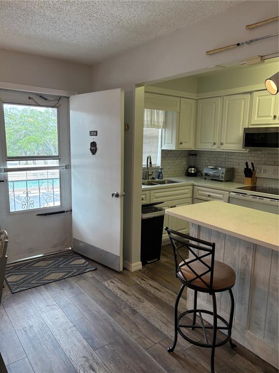 14531 Walsingham Road, Unit 204 Largo, FL 33774 - Photo 6 of 29 a kitchen with stainless steel appliances granite countertop a stove a sink dishwasher a microwave oven and a dining table with wooden floor