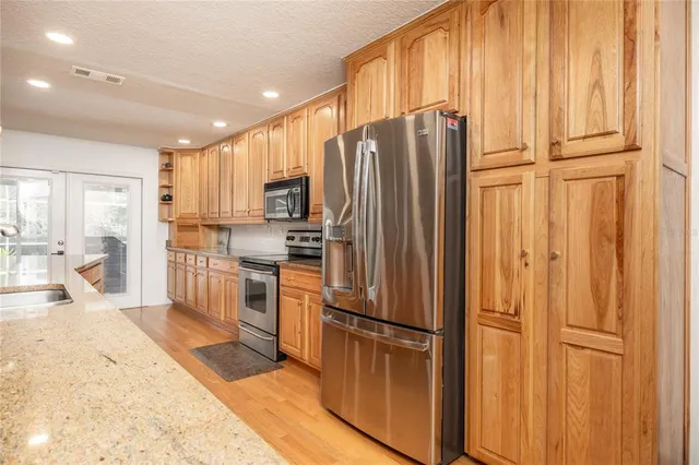 a large kitchen with stainless steel appliances a large counter top a stove and a sink