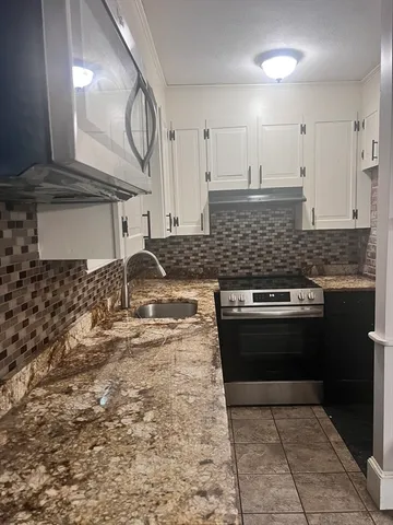a kitchen with granite countertop a stove and a sink