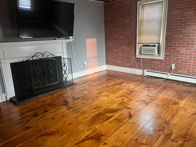 a view of an empty room with a fireplace and a window