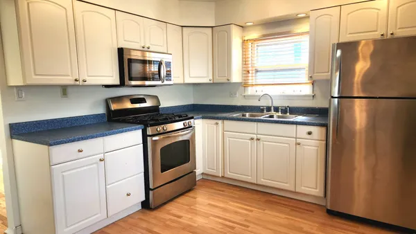 a kitchen with a refrigerator a stove a sink and dishwasher with wooden floor