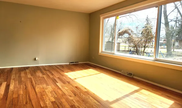 a view of a hallway with wooden floor and a bathroom