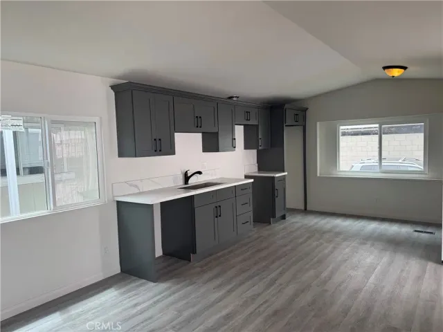 a kitchen with stainless steel appliances granite countertop a sink cabinets and wooden floor