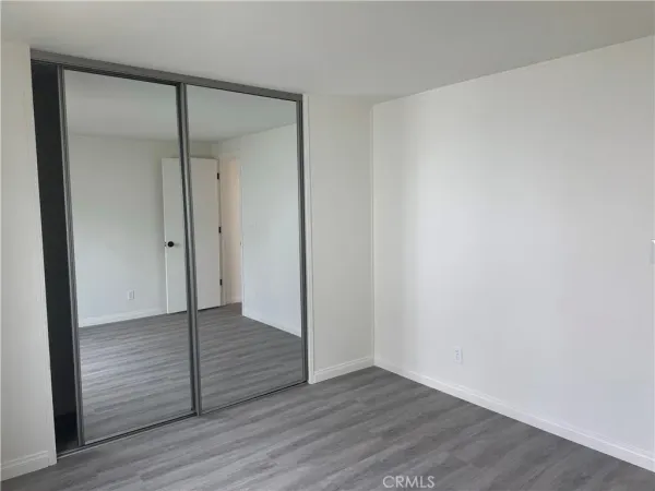 a view of an empty room with wooden floor and closet