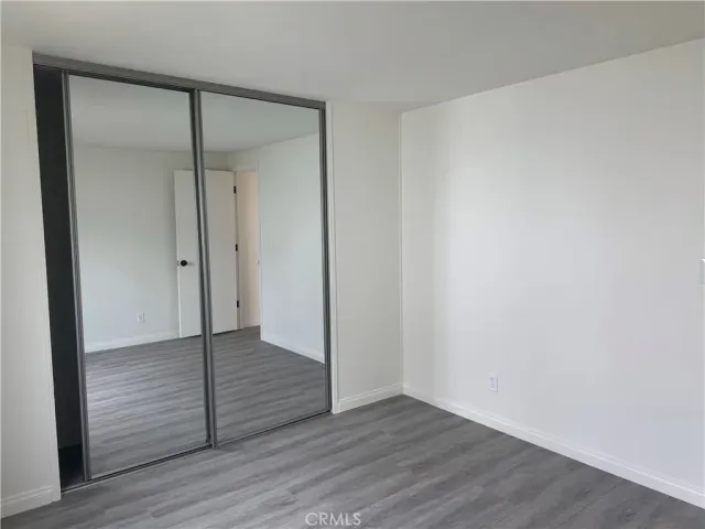 a view of an empty room with wooden floor and closet