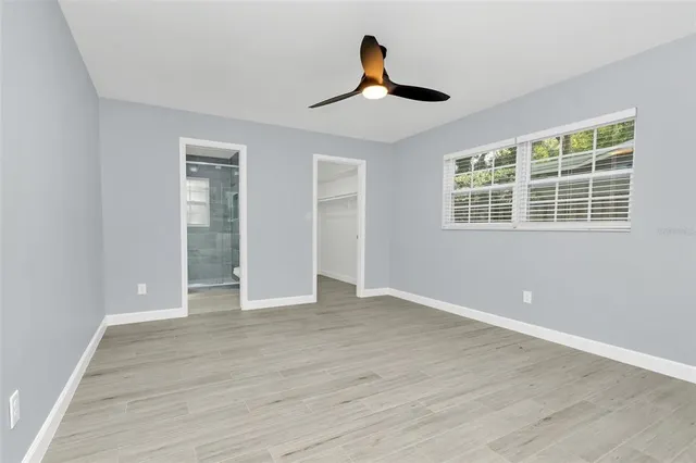 a view of empty room with wooden floor and fan