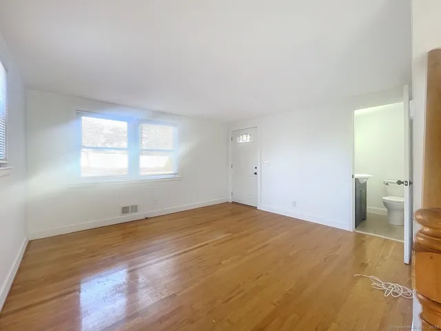 a view of empty room with wooden floor and window