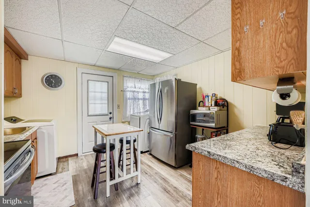 a kitchen with a refrigerator a stove top oven a sink dishwasher and dining table with wooden floor