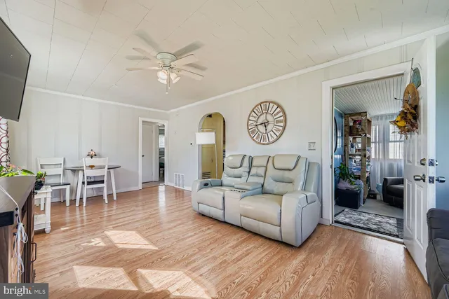 a living room with furniture a clock on wall and a window