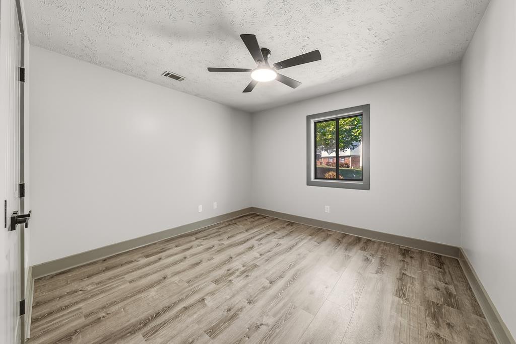 7313 Sesame Street Columbus, GA 31909 - Photo 27 of 43 an empty room with wooden floor ceiling fan and windows