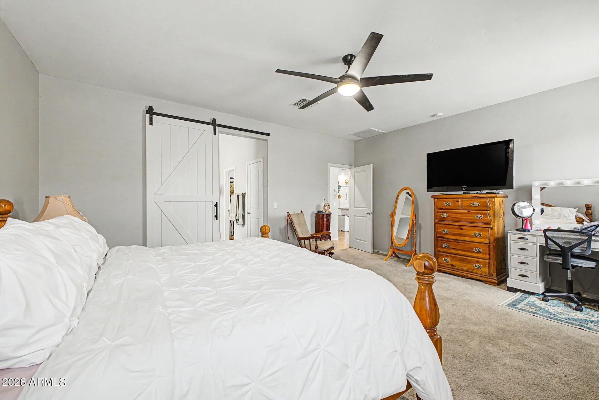 18021 West Indigo Brush Road Goodyear, AZ 85338 - Photo 15 of 47 a bedroom with a bed and a flat tv screen on dresser