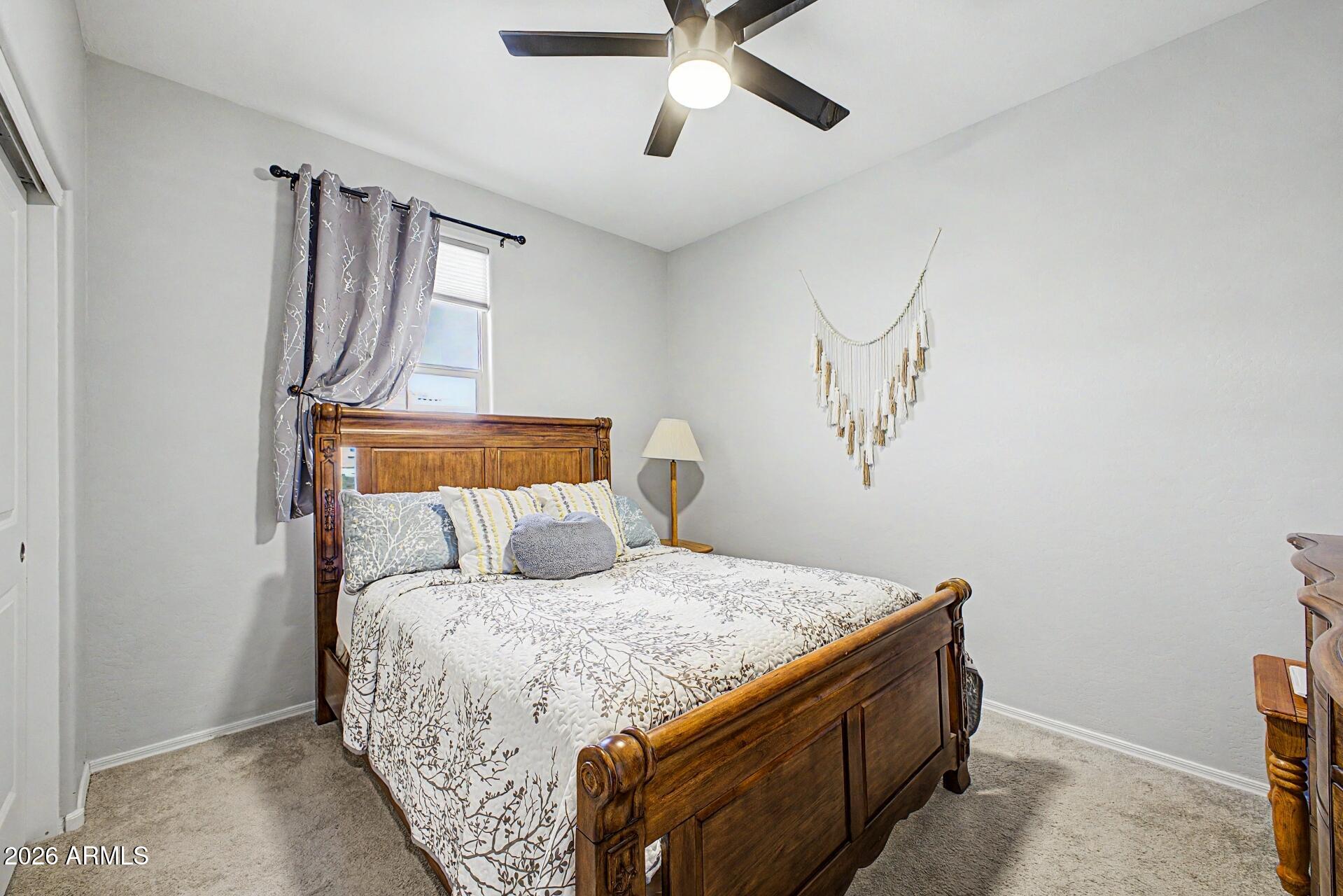 18021 West Indigo Brush Road Goodyear, AZ 85338 - Photo 18 of 47 a bedroom with a bed and a chandelier