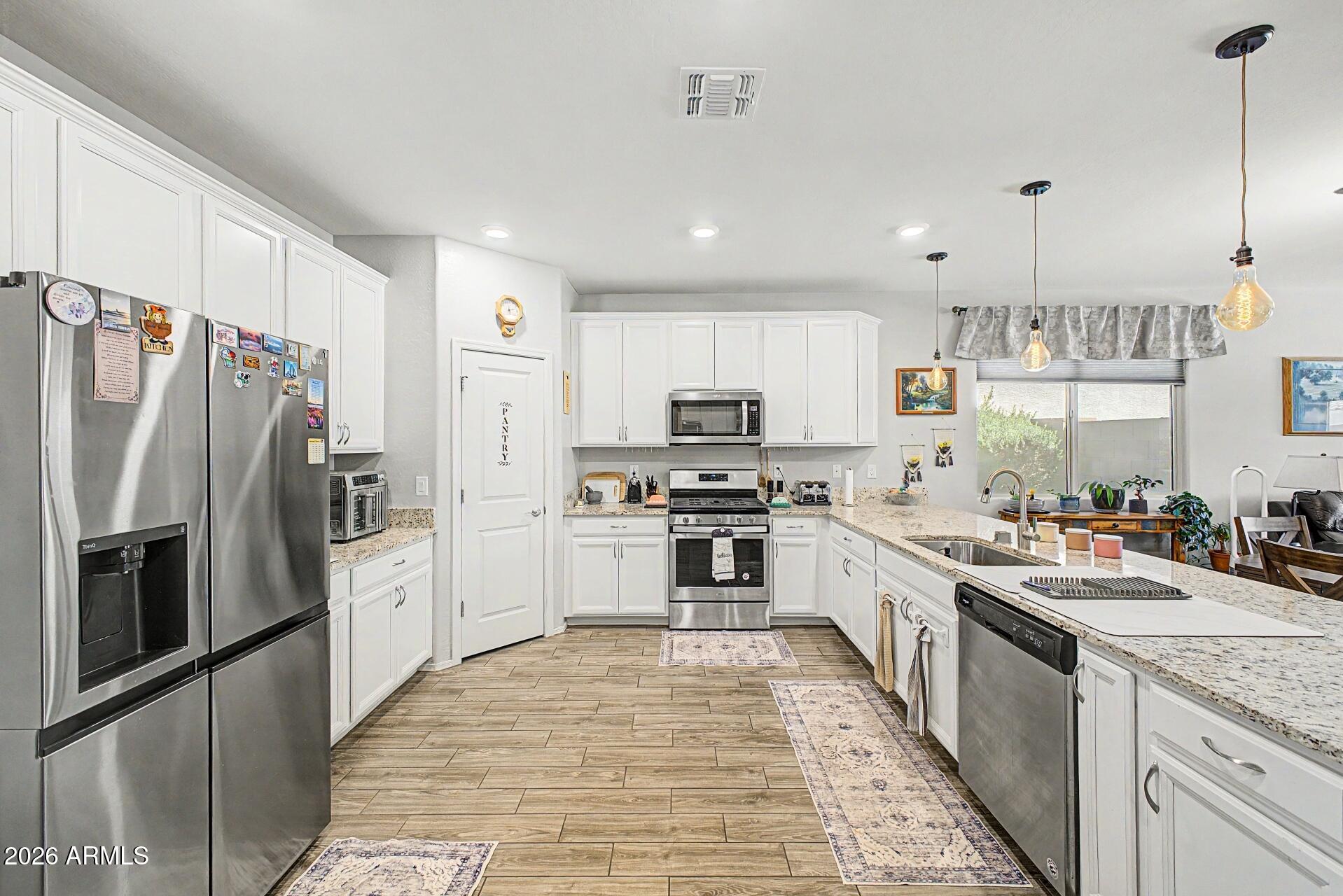 18021 West Indigo Brush Road Goodyear, AZ 85338 - Photo 4 of 47 a large kitchen with stainless steel appliances granite countertop a stove top oven a refrigerator a sink and dishwasher