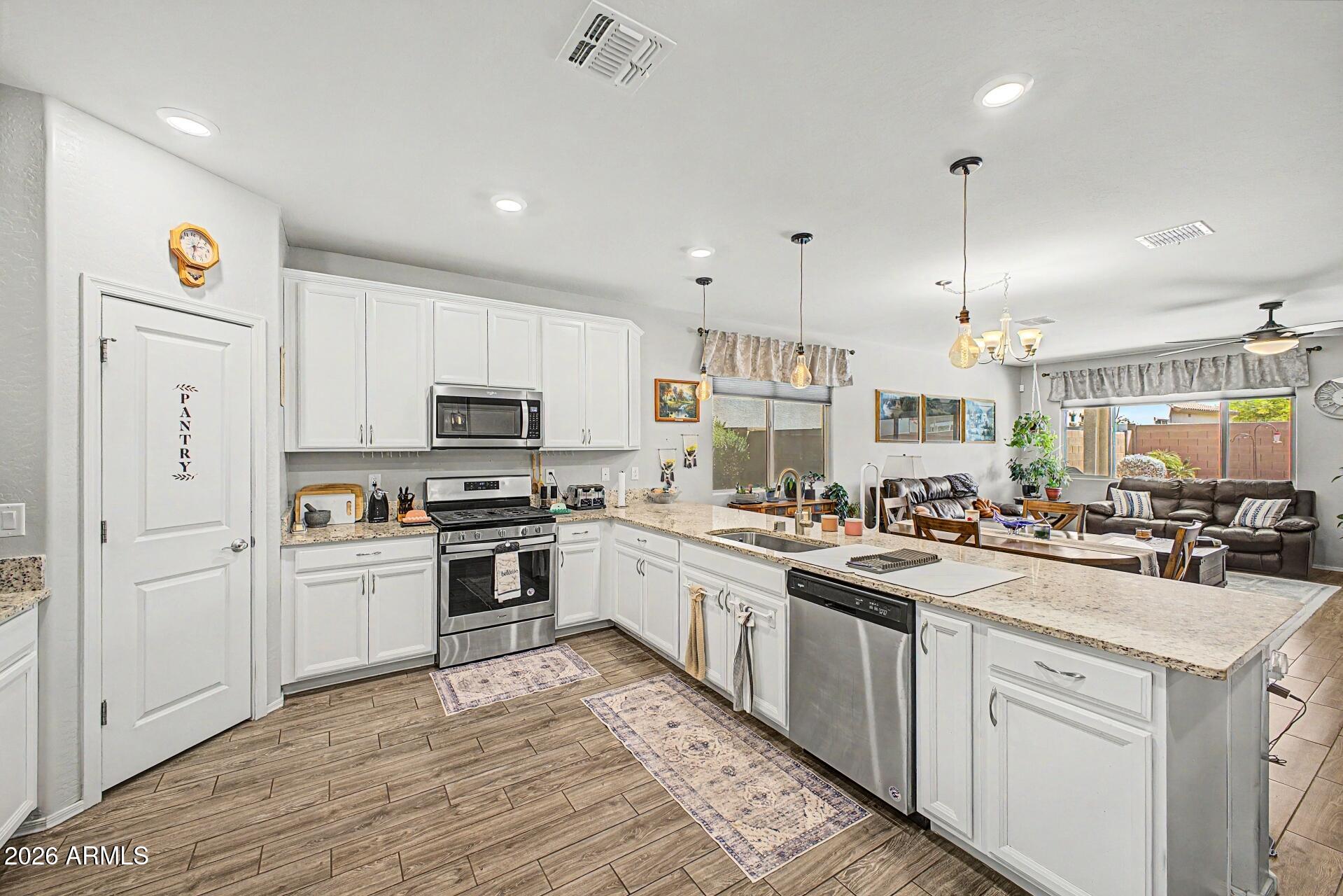 18021 West Indigo Brush Road Goodyear, AZ 85338 - Photo 9 of 47 a kitchen with white cabinets stainless steel appliances and sink