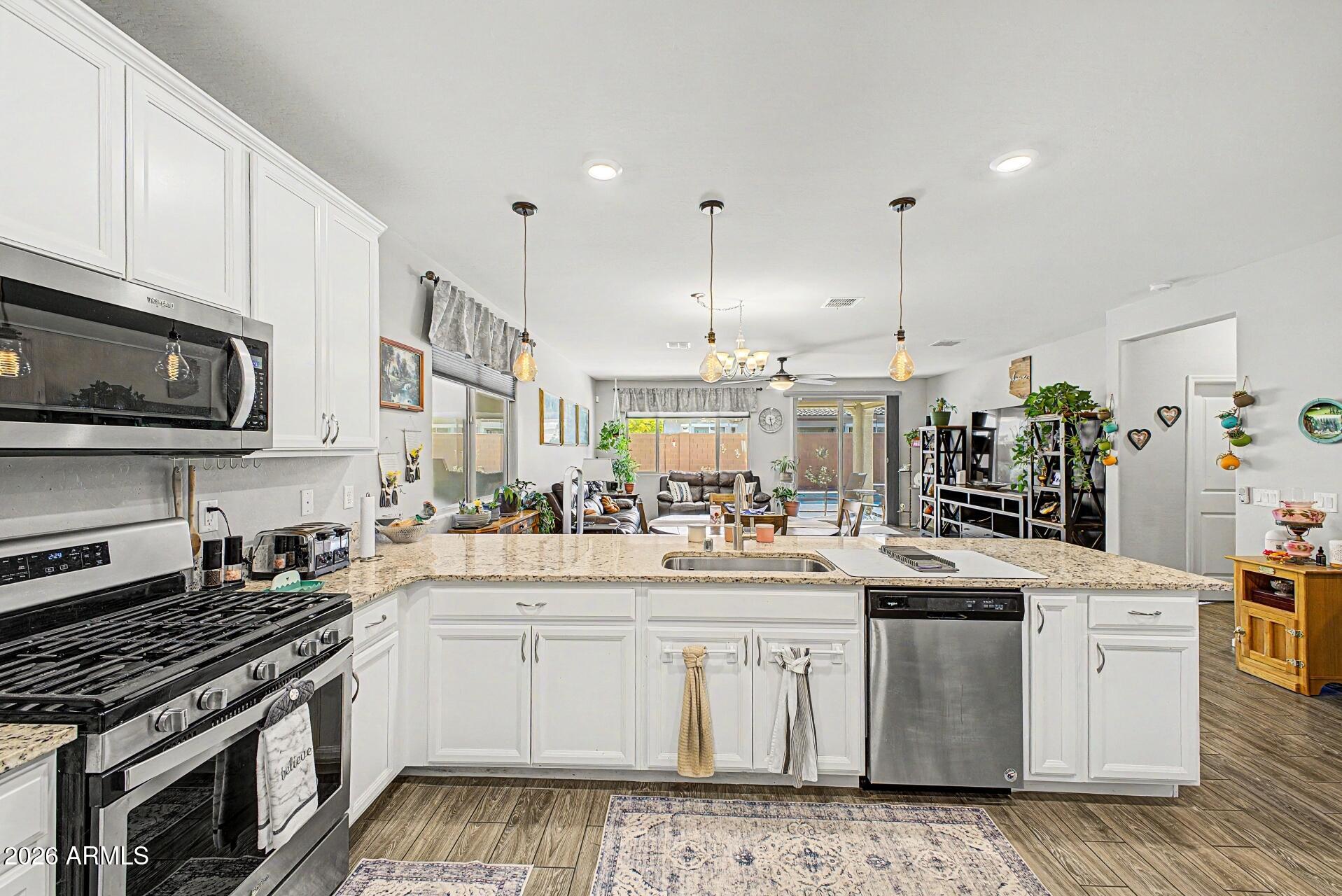 18021 West Indigo Brush Road Goodyear, AZ 85338 - Photo 10 of 47 a kitchen with stainless steel appliances granite countertop a sink stove and cabinets