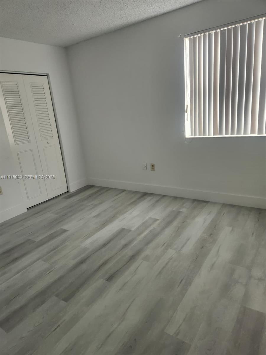 6272 Northwest 186th Street, Unit 201 Hialeah, FL 33015 - Photo 11 of 13 a view of an empty room with wooden floor and a window