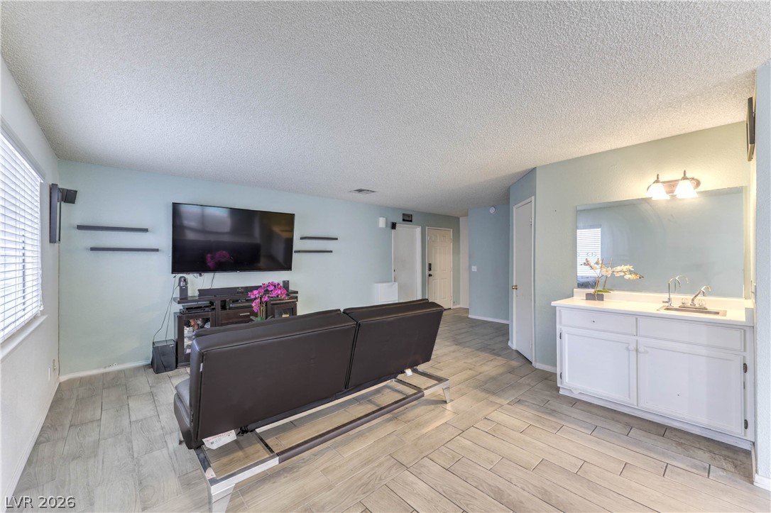 581 Carleton Drive Henderson, NV 89014 - Photo 4 of 37 Functional family room boasts light-toned plank flooring and an integrated wet bar.