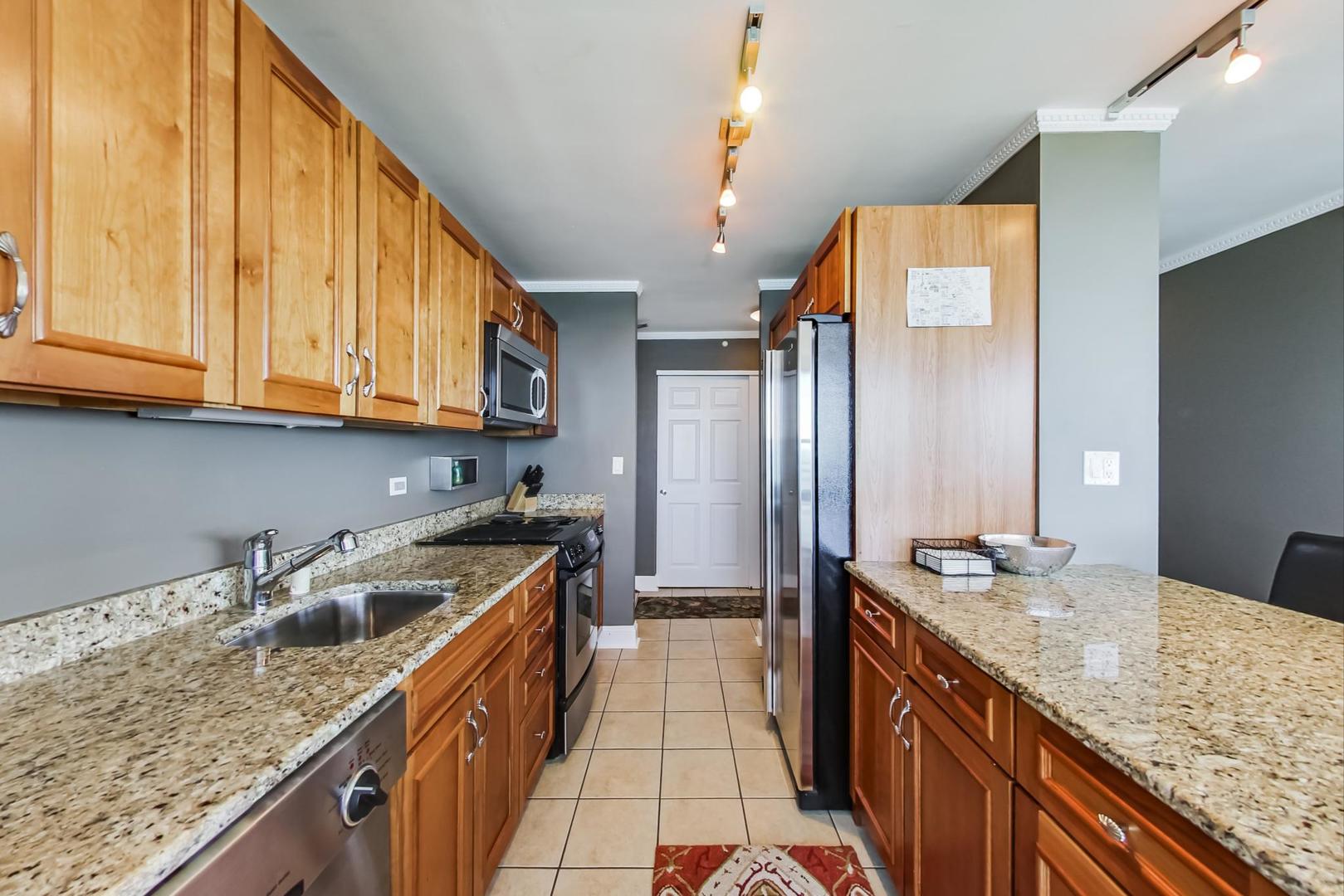 655 West Irving Park Road, Unit 3302 Chicago, IL 60613 - Photo 12 of 37 a kitchen with stainless steel appliances granite countertop a sink a stove and a wooden cabinets