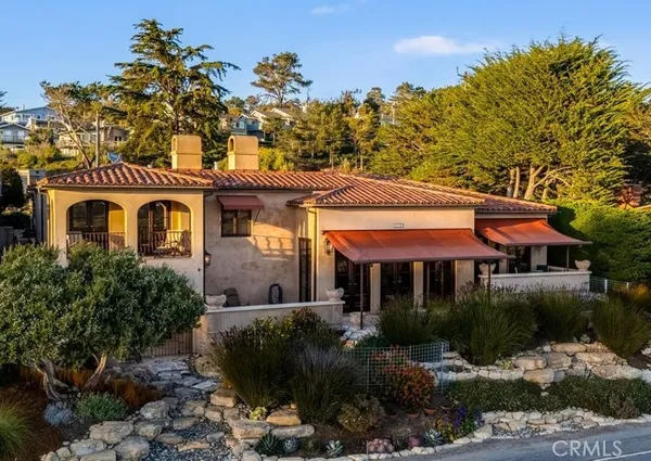 a front view of a house with a yard and mountain view in back