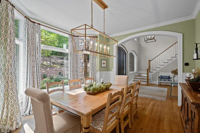 a view of a dining room and livingroom with furniture wooden floor a chandelier