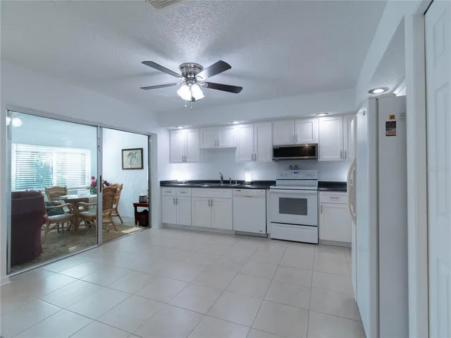 a large white kitchen with cabinets a sink and appliances