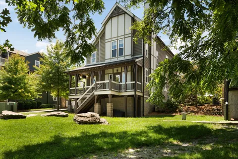 a view of a house with a yard and a large tree