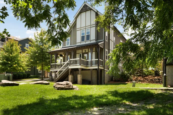 a view of a house with a yard and a large tree