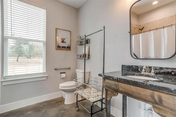 a bathroom with a granite countertop sink toilet and mirror