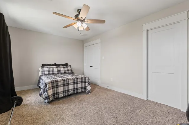 a room with two bed and a ceiling fan