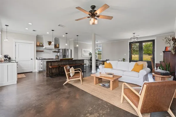 a living room with furniture kitchen view and a chandelier