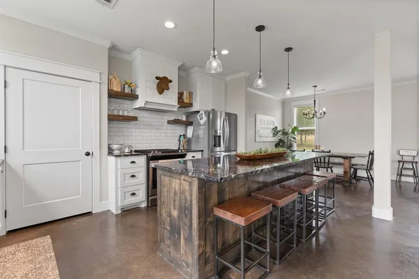 a kitchen with stainless steel appliances kitchen island granite countertop a stove a sink a dining table and chairs
