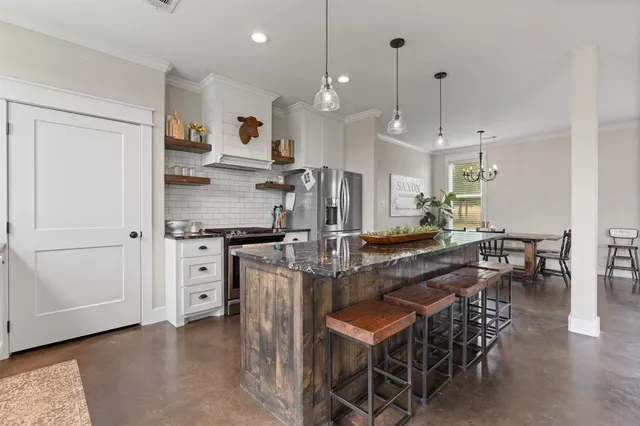 a kitchen with stainless steel appliances kitchen island granite countertop a stove a sink a dining table and chairs
