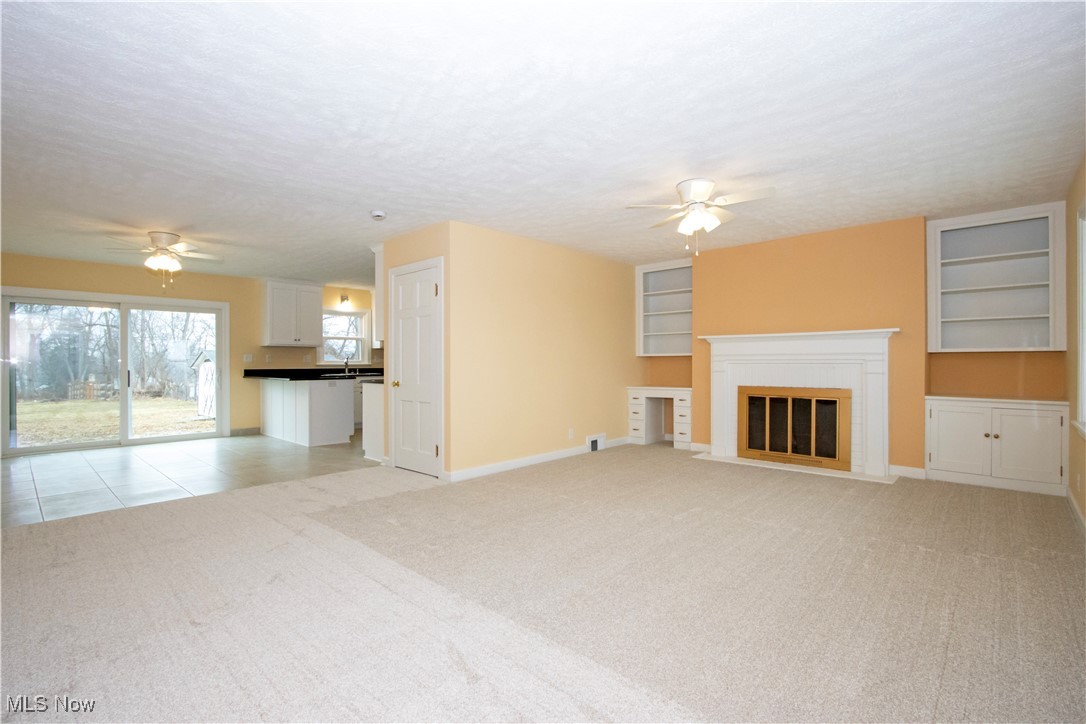 2467 Shreve Road Wooster, OH 44691 - Photo 4 of 27 Unfurnished living room with light carpet, ceiling fan, a textured ceiling, and a fireplace with flush hearth