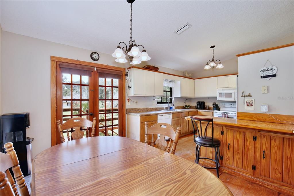 425 Mercers Fernery Road DeLand, FL 32720 - Photo 12 of 54 a open kitchen with stainless steel appliances granite countertop a stove top oven a refrigerator a dining table and chairs with wooden floor