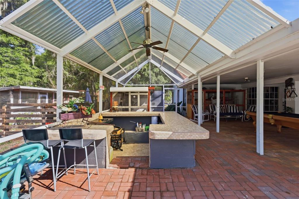 1898 Blackwelder Road De Leon Springs, FL 32130 - Photo 20 of 33 a view of a patio with table and chairs barbeque potted plants and large tree